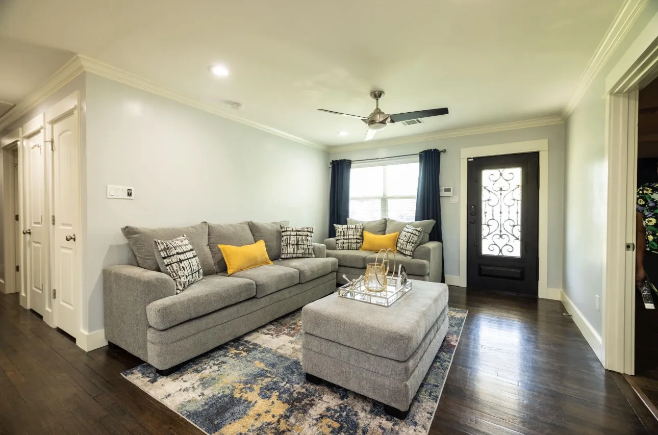 Bright living room with sofas, ottoman and hardwood floors cleaned by Goals Cleaning Services